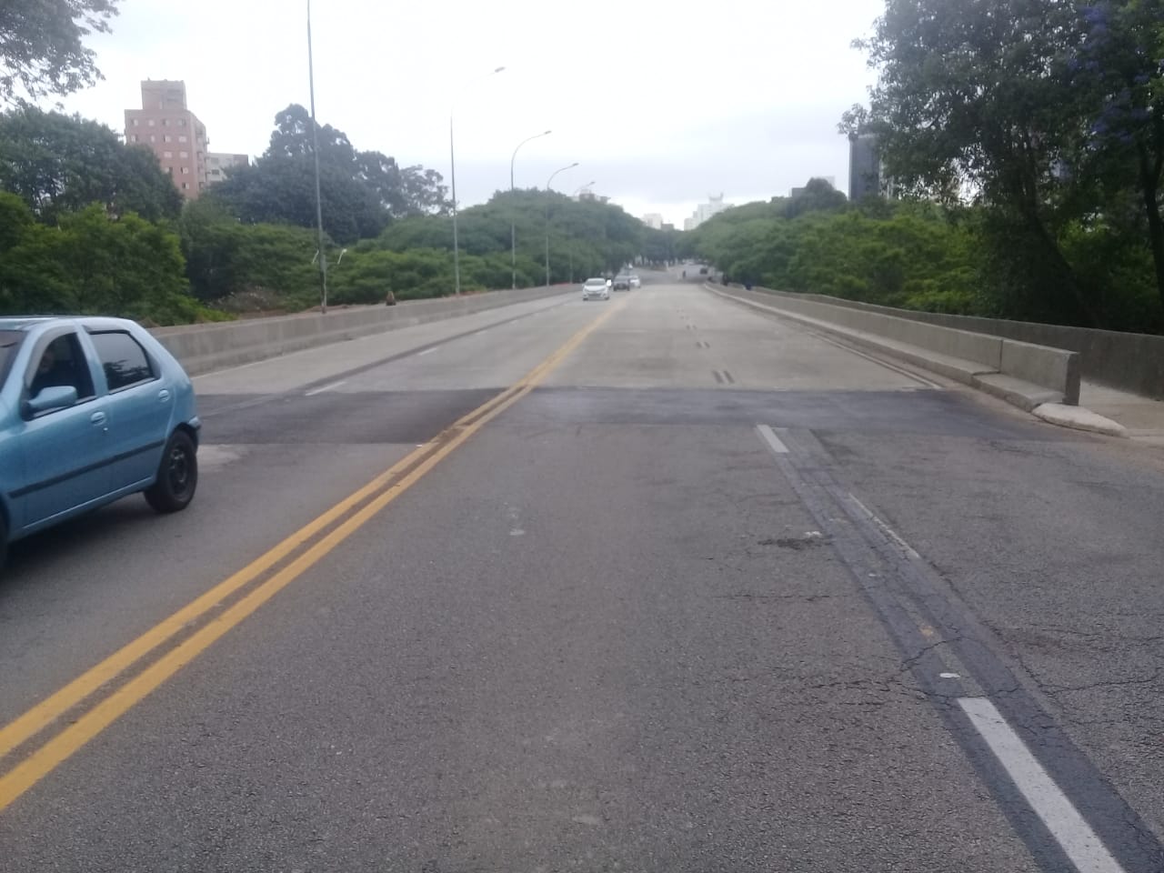 Fotografia de uma avenida com pouco movimento de veículos o dia está nublado